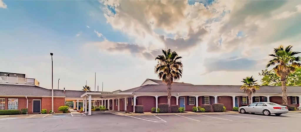 The covered front entrance and registration canopy at Winton Inn & Suites, with palm trees and the parking area